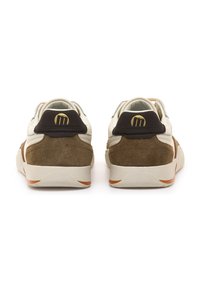 Weiße und braune Sneaker mit Wildledertextur, goldenem Logo und einer markanten Sohle mit orangefarbenem Akzent. Rückansicht zeigt den gepolsterten Kragen.