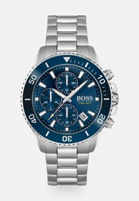 Montre en acier inoxydable avec un cadran bleu marine, sous-cadrans chronographe, aiguilles argentées et un affichage de la date. Caractéristiques d'une lunette texturée et d'un bracelet.