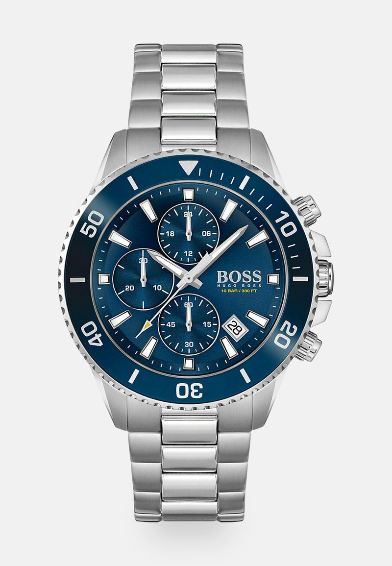Montre en acier inoxydable avec un cadran bleu marine, sous-cadrans chronographe, aiguilles argentées et un affichage de la date. Caractéristiques d'une lunette texturée et d'un bracelet.