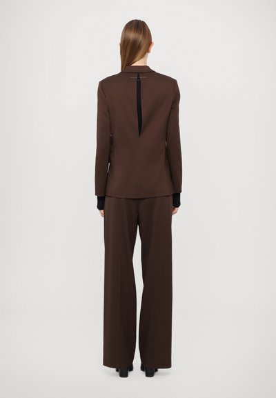 Brown tailored suit with a fitted jacket featuring a back vent and wide-leg pants. Smooth fabric with a matte texture and contrasting accents.