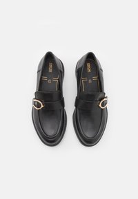 Paire de mocassins en cuir noir avec détail boucle dorée et semelles intérieures rembourrées de la marque Geox, vue de dessus sur fond blanc.