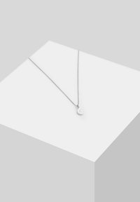 Collana d'argento con una catena delicata e un piccolo pendente a forma di luna crescente, caratterizzata da una finitura lucida e un lieve scintillio.