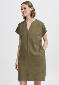 Vestido de lino verde oliva, de manga corta y escote en V, con dos bolsillos laterales. Silueta recta con ajuste relajado.