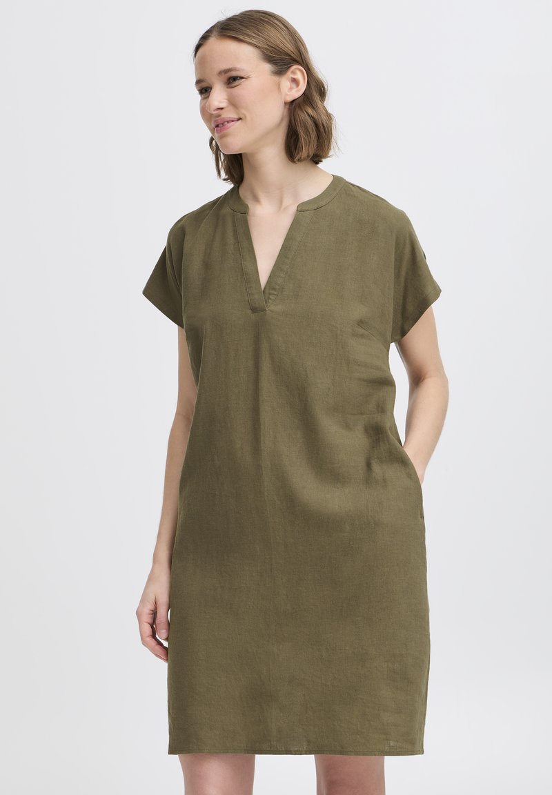 Vestido de lino verde oliva, de manga corta y escote en V, con dos bolsillos laterales. Silueta recta con ajuste relajado.