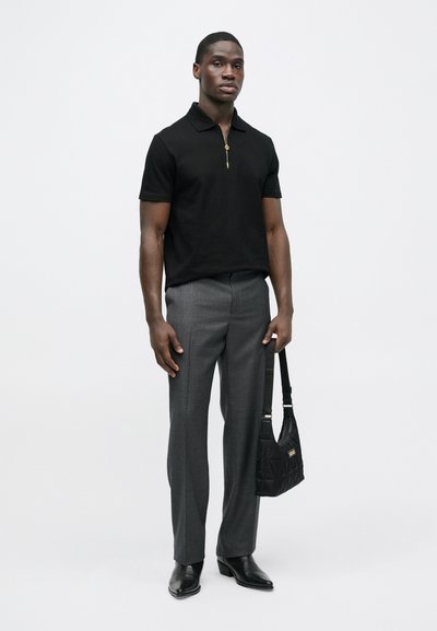 Juodas polo marškinėliai su užtrauktuku, pilki tekstūruoti kelnės, juodi odiniai batai ir juoda siuvinėta peties rankinė. Paprastas, modernus dizainas su prigludusia forma.