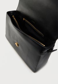 Μαύρη δερμάτινη τσάντα ώμου με ανοιχτό καπάκι, που αποκαλύπτει δύο θήκες με χρυσό φερμουάρ στο εσωτερικό και έναν χρυσό κυκλικό μαγνητικό κλείσιμο μπροστά.