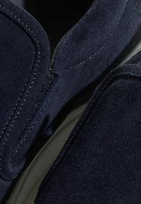 Suede mornarske cipele bez kopčanja, s glatkom završnom obradom, šivenim detaljima i bočnim patentnim zatvaračem za lakši pristup. Dizajn s zaobljenim prstom.