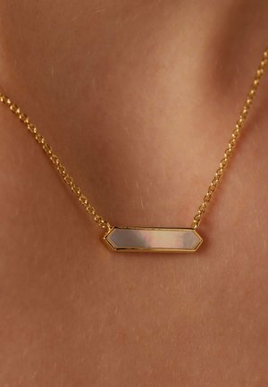 Collier en chaîne dorée avec un pendentif hexagonal à la surface lisse et irisée, reflétant des couleurs douces. Design minimaliste, finition élégante.