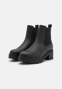 Bottines en cuir noir avec panneaux latéraux élastiques, finition texturée, talon bloc et semelle en caoutchouc avec un design cranté.