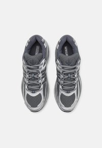 Par nogavic sivi in srebrni Adidas za tek s čipkami, pogledano od zgoraj na belem ozadju.