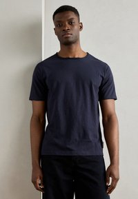 Marineblaue Kurzarm-T-Shirt mit rundem Ausschnitt und lockerer Passform. Weicher Stoff, dezente Seitennähte und gerader Saum.
