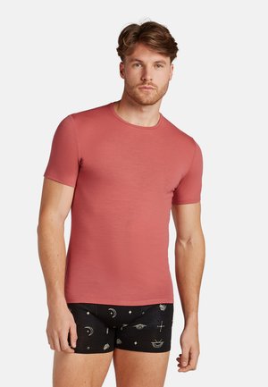 Kortebreder, getailleerd t-shirt in stoffige roos, gemaakt van zachte stof. Gepaard met zwarte boxershorts met hemelse patronen in het wit.