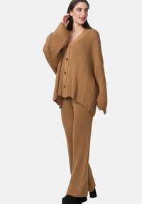 Ribbel gebreide cardigan en broekset in taupe, met een V-hals, oversized pasvorm en knoopsluiting op de cardigan. Geweven stofaccenten.