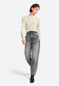 Pull en tricot multicolore pastel à manches longues, associé à un jean en denim gris taille haute. Des chaussures noires complètent la tenue.