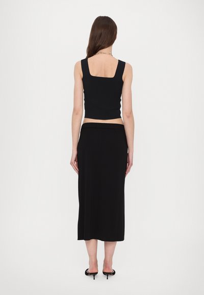 Black cropped tank top with a square neckline paired with a black ankle-length skirt. Smooth fabric and elastic waistband.