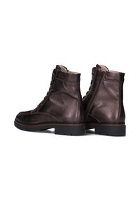 Bruine lederen enkellaarzen met een gestructureerde afwerking, vetering aan de voorkant en een rits aan de zijkant, met een dikke zwarte rubberen zool en minimale stiksels.