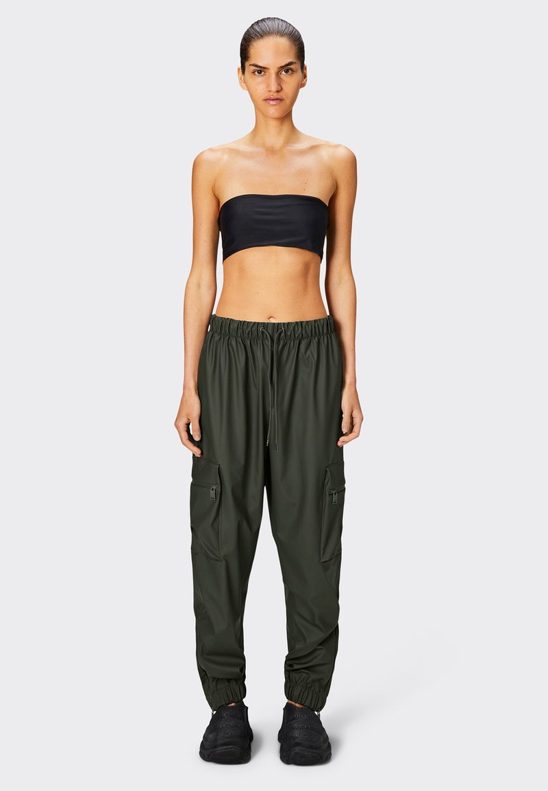 Pantaloni cargo verde scuro con polsini elasticizzati, molteplici tasche laterali e vita con cordoncino, abbinati a un top nero senza spalline.