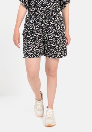 Sort og creme mønstrede shorts med elastisk talje, prydet med et blomsterdesign og sidelommer, parret med lette sneakers.