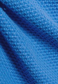 Blaues, strukturiertes Gewebe mit einem gewebten Muster, das eine weiche, taktile Oberfläche aufweist. Das Gewebe wirkt leicht und fällt mühelos.