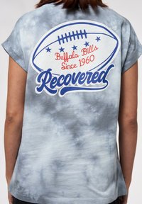 Blått tie-dye t-shirt med korta ärmar har en fotbolls grafik och text som säger "Buffalo Bills Sedan 1960" och "Återvunnen" i röd och blå.