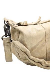 Sac en cuir doré métallique avec une surface texturée, fermeture éclair et bandoulière en tissu réglable avec clips en métal. Forme arrondie et bords doux.