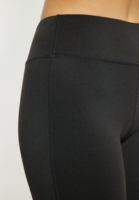 Zwarte legging gemaakt van glad, rekbaar materiaal met een hoge taille. Kenmerkt zich door platte naden en een slanke, aansluitende ontwerp.
