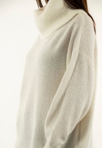 Crème-kleurige coltrui van zachte wol, met een losse pasvorm, dropped shoulders en geribbelde accenten bij de kraag en manchetten.