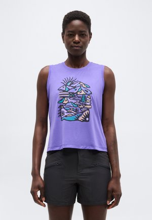 Femeie purtând un top fără mâneci violet cu un imprimeu abstract colorat cu motive naturale și pantaloni scurți negri cu fermoar, stând pe un fundal alb.