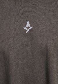 Mørkegrå t-shirt med en blød tekstur, der har et hvidt stjernelogo foran, placeret lidt off-center.