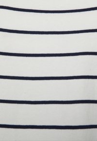 Vitt tyg med marinblå horisontella ränder, med en mjuk textur och stickat mönster. Ränderna varierar i bredd för visuell intresse.