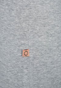 Gray cotton fabric with a subtle texture. Features a small rectangular orange label with a circular design near the seam.
