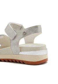 Sandalias gris claro con cuero texturizado, correas ajustables, suela gruesa y una base de goma marrón contrastante. Detalles de acento en plata.