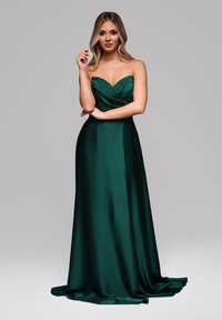 Suknia wieczorowa w odcieniu szmaragdowej zieleni z satyny, z dekoltem w kształcie serca, drapowaną górą oraz zwiewnym dołem, charakteryzująca się gładką teksturą i elegancką linią.