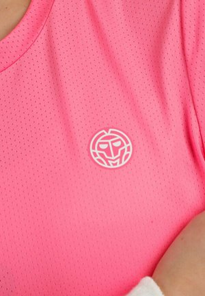 Primo piano di tessuto rosa perforato con un piccolo logo astratto bianco a forma di volto stampato vicino all'area del petto.