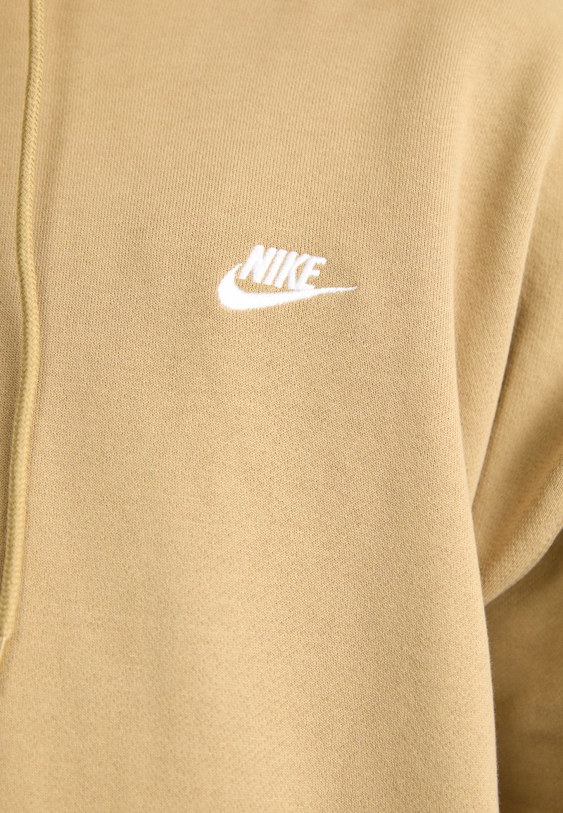 Sweatshirt beige en tissu doux au toucher lisse. Présente un logo Nike blanc brodé sur la poitrine. Design simple sans motifs.