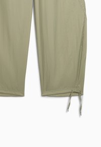 Pantaloni cropped verde oliva chiaro realizzati in tessuto leggero. Presentano un dettaglio con coulisse all'orlo e tasche laterali. Tessuto liscio.