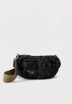 Kleine schwarze Stoff-Bauchtasche mit mehreren Vordertaschen, silbernem Reißverschluss und kurzem breitem beigem Riemen vor weißem Hintergrund.