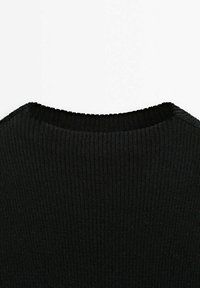 Gros plan sur un tissu noir en maille côtelée montrant l'encolure et la texture d'un pull ou d'un haut.
