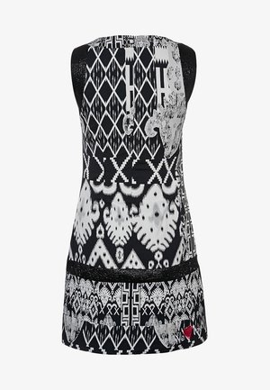 Tunique sans manches noir et blanc présentant des motifs géométriques complexes, un tissu lisse et une accent en dentelle à l'ourlet.