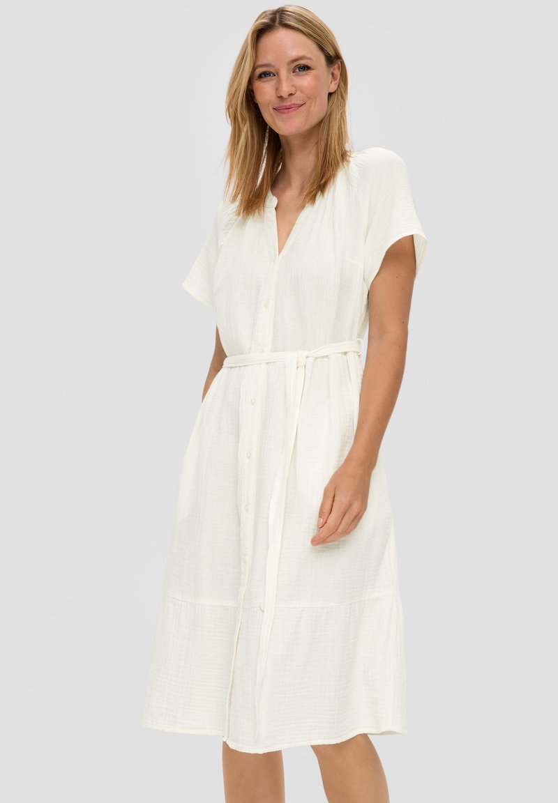 Witte, knoopsluiting jurk met korte mouwen, getailleerde taille en gelaagde onderrand. Gemaakt van textuurstof, heeft een relaxte pasvorm.