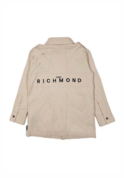Giacca beige con cuciture verticali e la scritta "JOHN RICHMOND" in lettere nere in grassetto sul retro, con maniche a bottone e colletto.