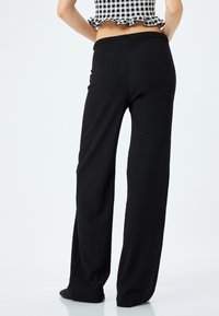 Zwarte wijde broek van een textuurstof met een elastische tailleband, met een losse pasvorm en een rechte pijpsilhouet.