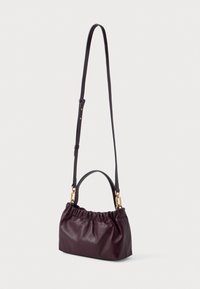 Burgundinės odos rankinė su surinktu dizainu, turinti viršutinę rankeną ir nuimamą ilgą diržą su auksiniais akcentais.