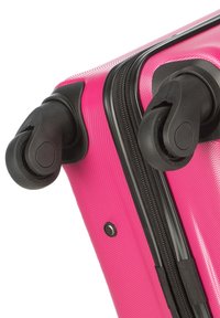 Valigia rigida rosa con superficie testurizzata, dotata di due ruote girevoli nere e una cerniera nera lungo il lato.