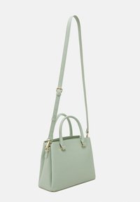 Mintgrön läderhandväska med en strukturerad design, dubbla topphandtag och en avtagbar lång rem. Guldiga detaljer.