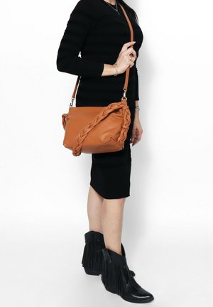 Borsa a tracolla in pelle beige con design intrecciato, dotata di una tracolla. Il materiale sembra liscio con una consistenza morbida. Nessun dettaglio hardware visibile.