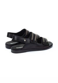 Sandalias de piel negra con tres gafas anchas y costuras doradas. Diseño de parte trasera abierta y suela plana para mayor comodidad.