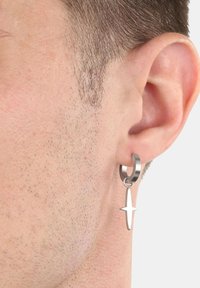 Pendiente de aro de metal con un charm colgante en forma de estrella de plata. El diseño presenta un estilo elegante y minimalista con un acabado brillante.