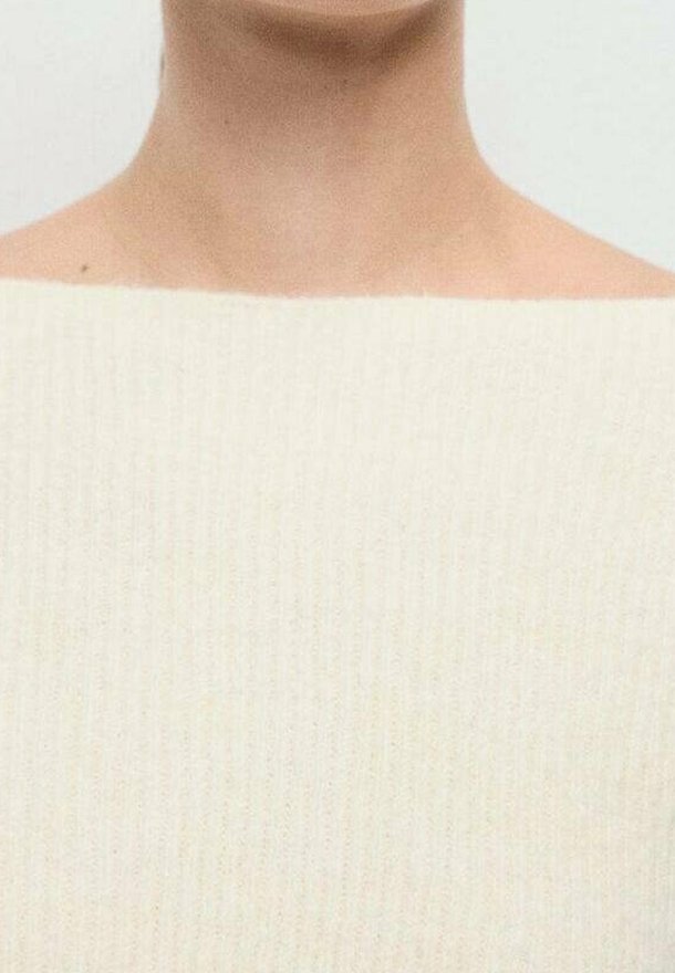 Gros plan sur le cou et les épaules d'une personne portant un pull en tricot côtelé de couleur crème avec un large col carré.