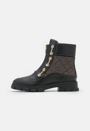 Bottine en cuir noir avec panneau en tissu matelassé, œillets en chaîne dorée, col rembourré et semelle épaisse à crampons.
